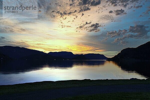 Fjord with sunset and illuminated clouds in the sky. View of mountains and fjord landscape in Norway. Landscape shot in the evening in the north