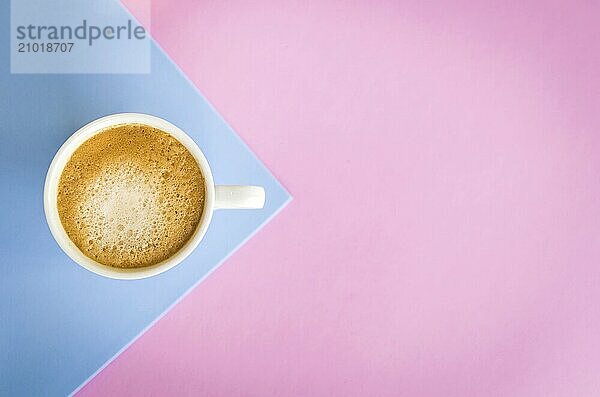 White cup of coffee on light pink and light blue background