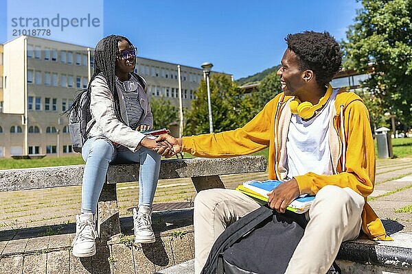 African american students shaking hands sitting on staircases on the campus