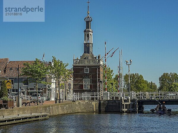 A historic tower next to a bridge over a canal on a sunny day  alkmaar  the netherlands