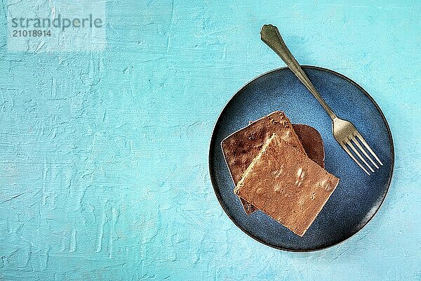 Chocolate brownie  simple coffee cake  overhead flat lay shot on a vibrant blue background  on a plate with a fork  with a place for text  Food photography