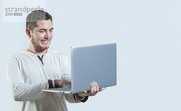 Excited guy holding and looking at an promotion on laptop screen. Portrait of happy young man standing using laptop isolated