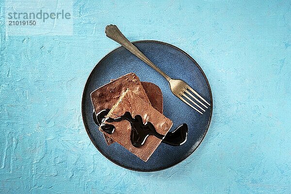 Chocolate brownie with syrup  simple coffee cake  overhead flat lay shot on a vibrant blue background