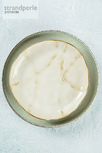 An empty plate with a gold rim  top shot on a slate background  modern tableware