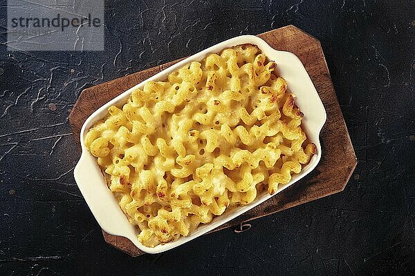 Macaroni and cheese pasta in a casserole  overhead shot on a black background. Traditional American comfort food