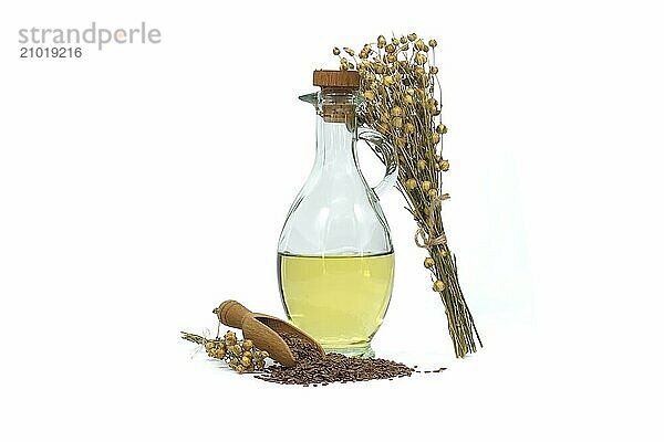 Linseed oil in glass decanter and flax seeds in wooden scoop and bunch of flax plants isolated on white background. Linum usitatissimum (Common Flax)