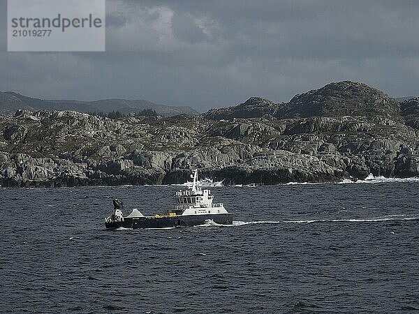 A fishing vessel sails off the rocky Norwegian coast