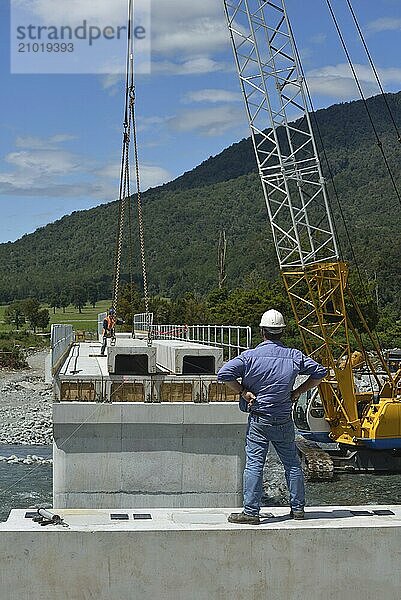 Builders construct a concrete bridge over a small river in Westland  New Zealand  Oceania