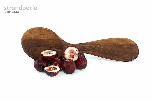 Fresh cranberries and cranberry berry cut in half in front of wooden spoon isolated on white background