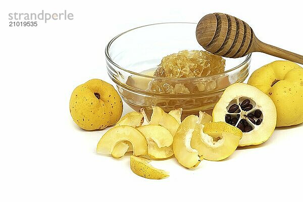 Glass with honey surrounded by vibrant quince fruits  both sliced and whole isolated on white background  full depth of field