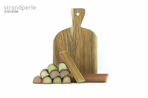 Rhubarb stalks of varying colors from pale green to deep red in front of wooden cutting board isolated on white background  illustrate a recipe for a rhubarb-based dish