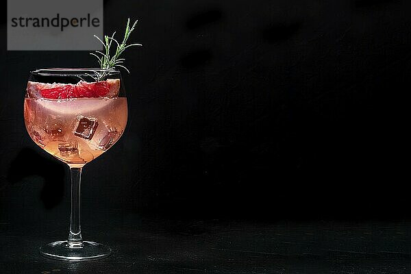 Fancy cocktail with fresh fruit. Gin and tonic drink with ice at a party  on a black background. Alcohol with pink grapefruit and rosemary  with copy space  Food photography  Food photography