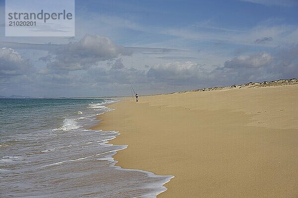 Fisherman fishing on a Comporta empty beach with ocean waves on the sand in Portugal