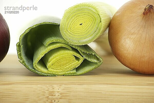 Sliced fresh leek next to yellow onion isolated on white background