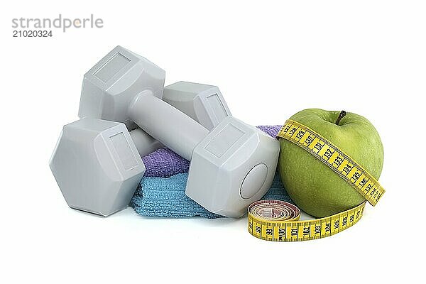 Health and fitness equipment including two gray dumbbells  green apple with a tape measure wrapped around it isolated on white background