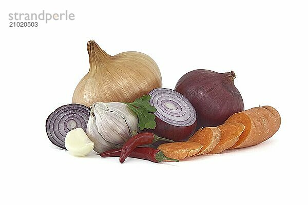 Collection of vegetables consisting red and yellow onions  red chili peppers  bulb of garlic and sliced carrots isolated on a white background