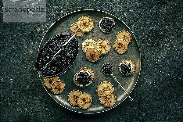 Blinis with black caviar and cream cheese  overhead flat lay shot on a black background  mini pancakes  an elegant appetizer  Food photography  Food photography