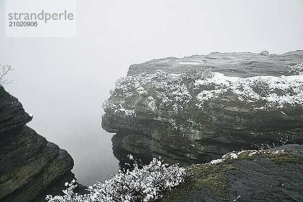 On the large Zschirnstein in fog. Rock covered with snow. Viewpoint during a hike. From the nature park in the Elbe Sandstone Mountains. Landscape in Germany