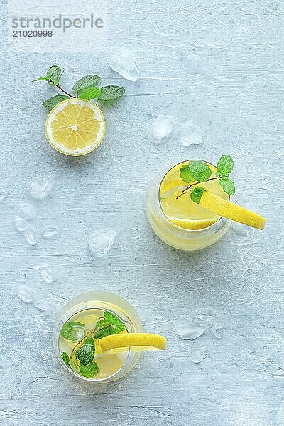 Lemonade with mint. Lemon water drink with ice. Two glasses and a pitcher on a pastel background  overhead flat lay shot. Detox beverage. Fresh homemade cocktail