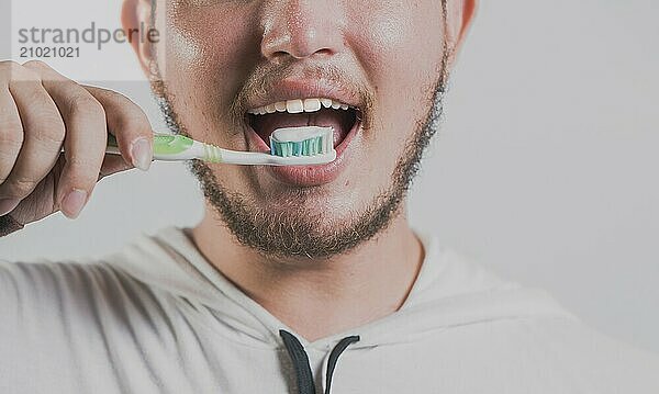 Health and tooth brushing concept. Smiling man brushing teeth isolated