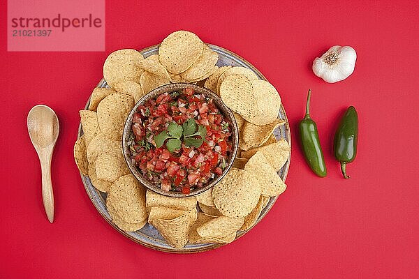 A view from above of chips and homemade salsa on a red background