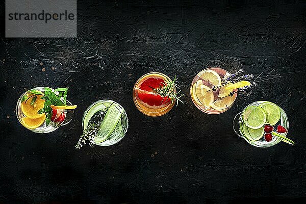 Fancy cocktails with fresh fruit. Gin and tonic drinks with ice at a party  on a black background  overhead flat lay shot  Food photography