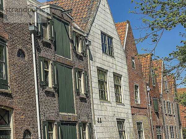 Old brick houses with shutters along a canal on a sunny day  alkmaar  the netherlands