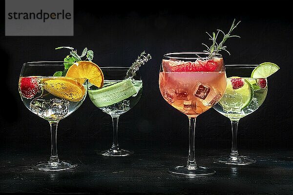 Fancy cocktails with fresh fruit. Many gin and tonic drinks with ice at a party  on a black background. Alcohol with herbs and flowers  Food photography  Food photography