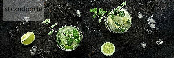 Mojito cocktail overhead flat lay panorama. Summer cold drink with lime  fresh mint  and ice. Cool beverage on a black background  Food photography