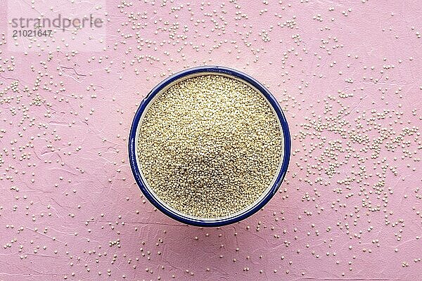 Quinoa in a bowl  healthy organic wood  uncooked  overhead shot on a pink background