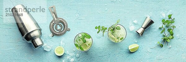 Mojito cocktail overhead panorama. Summer cold drink with lime  fresh mint  and ice. Cool beverage on a blue background  a flat lay shot with a shaker  Food photography  Food photography