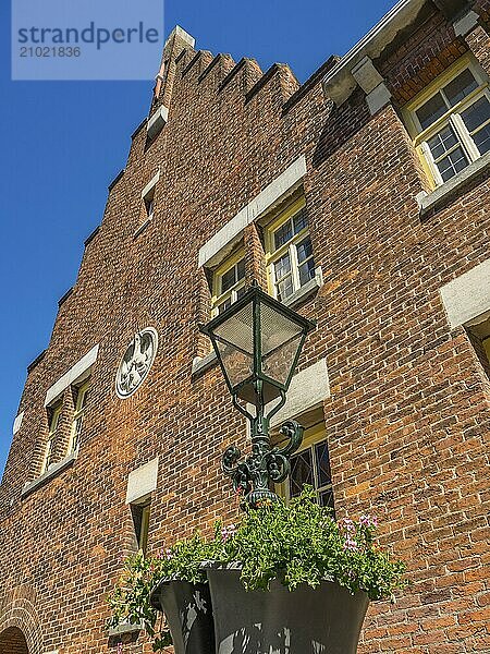 Brick building with decorative windows  a flower bed and a lantern against a clear sky  alkmaar  the netherlands