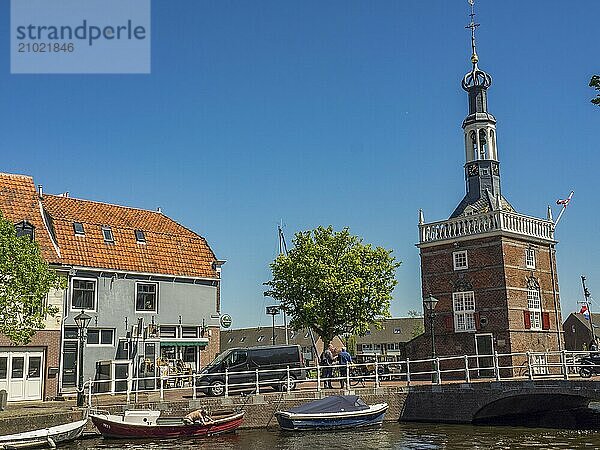 A historic tower overlooks a canal with boats and a bridge on a sunny day  alkmaar  the netherlands