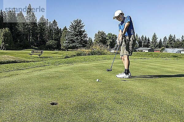 An older boy makes a putt on a bright and sunny day in Coeur d'Alene  Idaho