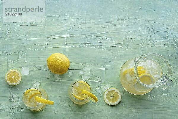 Lemonade. Lemon water drink with ice. Two glasses and a pitcher on a blue background  shot from the top with a place for text. Detox beverage. Fresh homemade cocktail  Food photography  Food photography