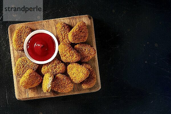 Chicken nuggets with ketchup on a dark background  shot from the top with copy space. A crispy appetizer at a restaurant  finger food  Food photography  Food photography