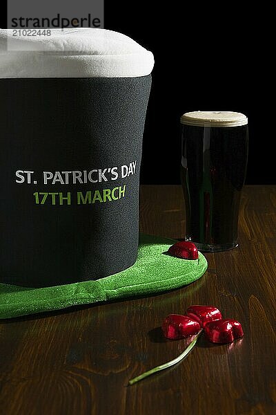 St Patrick day with a pint of black beer  hat and shamrock over a table and black background