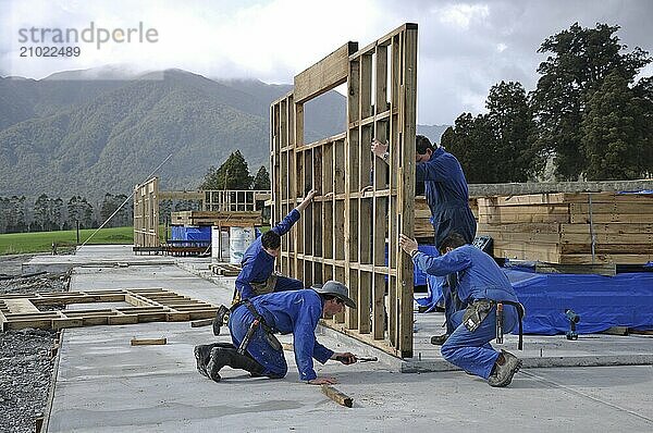 Builders stand up a wall framing section on a large building