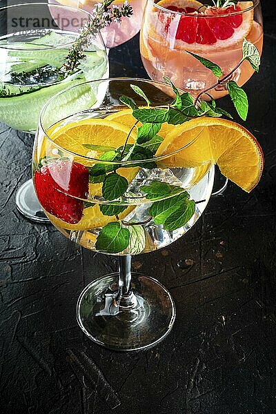 Fancy cocktails with fresh fruit. Gin and tonic drinks with ice at a party  on a black background. Alcohol with mint  cucumber  citrus fruits  a variety