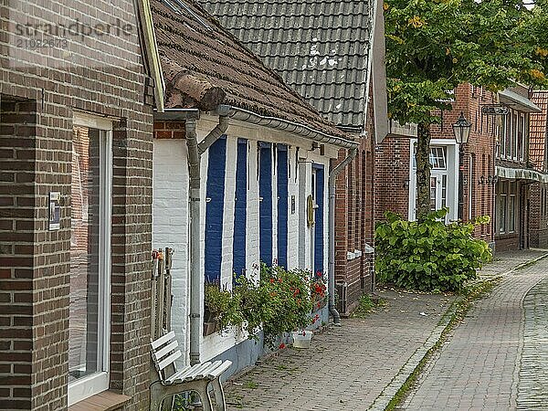 Street with traditional old houses made of brick and wood  decorated with flowers  dornum  east frisia  germany