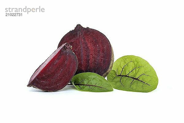 Slices of beetroot revealing their vibrant purple interiors complete with their fresh green leaves set against white background