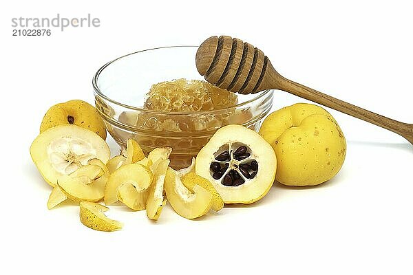 Glass with honey surrounded by vibrant quince fruits  both sliced and whole isolated on white background  full depth of field