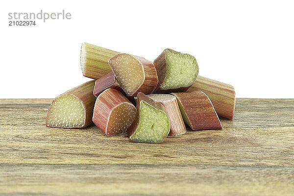 Variety of rhubarb stalks of varying colors from pale green to deep red on wooden cutting board isolated on white background