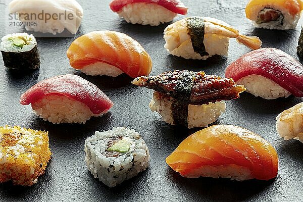 Sushi. Rolls  maki  nigiri on a black background  Japanese food. Salmon  tuna  eel  shrimp and other seafood with rice on a plate at an Asian restaurant  Food photography  Food photography