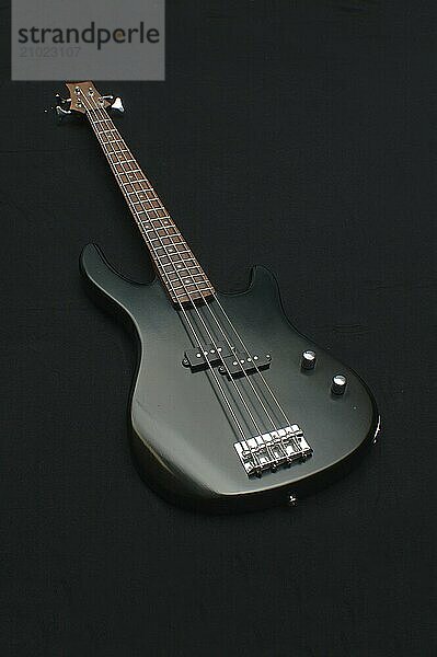 Black electric bass guitar on black background