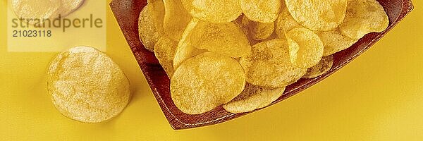 Potato chips or crisps  a salty snack on a yellow background  a panoramic banner  top shot  Food photography