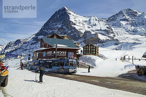 25 March 2024  Kleine Scheidegg  Grindelwald Switzerland : Many skiers and tourists enjoy the sunny winter weather. In the background the famous north face of the Eiger  in the foreground the Wengernalp railway  the longest cog railway in the world