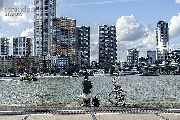 Skyline at the Nieuwe Maas  skyscrapers  man taking a break at the riverbank  Rotterdam  Netherlands