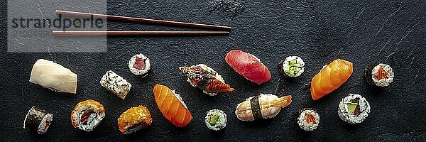 Sushi overhead flat lay panorama with chopsticks. Rolls  maki  nigiri on a black slate background  Japanese food. Salmon  eel  shrimp  tuna etc with rice