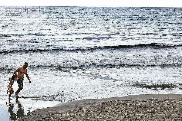 A father runs with his daughter on the beach of Diana Marina  Italy  18/08/2024  Diano Marina  Liguria  Italy  Europe